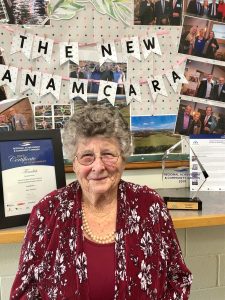 Image of a woman in front of a pin board with photos and awards